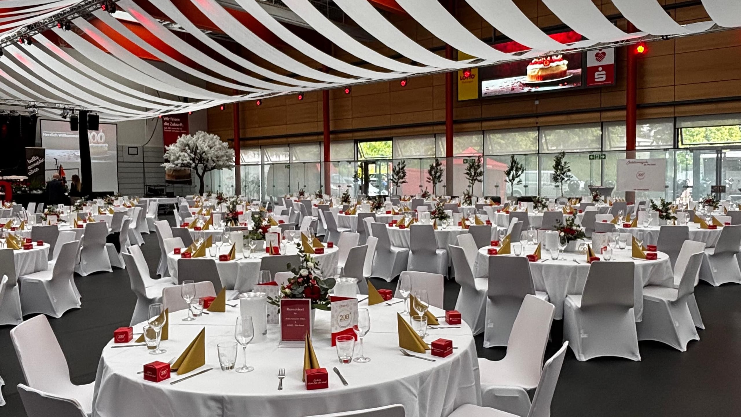 Festsaal mit Deckenbahnen, runden Tafeln und Stuhlhussen